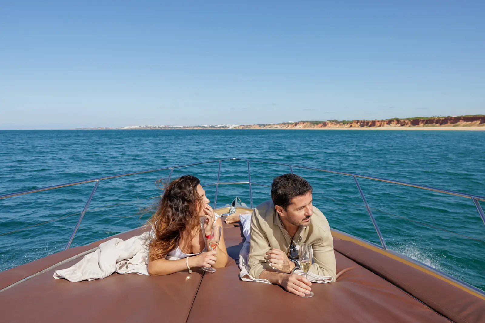 Couple lounging on the bow of the yacht with champagne and ocean views